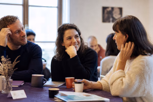 Un petit groupe d’adultes discute autour d’un café lors d’une rencontre associative.