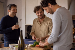 Trois hommes préparent le dîner ensemble dans la cuisine de leur appartement.